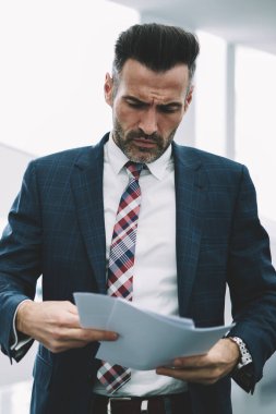 Formal giyim ofis iç mali raporlar kontrol emin olgun işadamı giymiş. Şık takım elbise okuma kağıt üzerinde yazılı bilgi veri bankacılık dalgın orta yaşlı girişimci