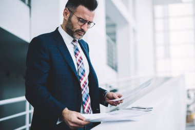 Konsantre akıllı işadamı dikkatle mali metin belgeleri okuma takım elbise giymiş. Formal giyim bilgi verilerle çalışma office metin raporları çözümleme dalgın gurur CEO'su giymiş