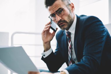 Ofiste çalışan Smartphone için işlecini çağırmak ellerinde mali metin raporlarla emin başarılı iş adamı. Gurur CEO'su 50 yaşında belgeler üzerinde telefon bankacılığı ile deneyimli