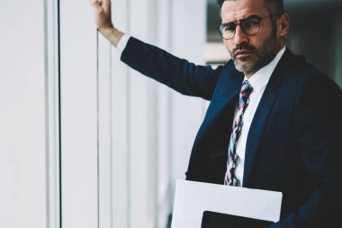 Kendine güvenen başarılı işadamı modern tablet aygıtı elinde tutan ve kameraya bakarak 50 yaşında yarım uzunluk portre. Finans şirketinin ciddi olgun sahibi formal giyim giyinmiş