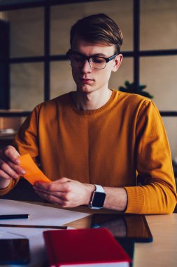 Kafkas istihbaratından erkek öğrenci modern sınıfta ders çalışırken hatırlatma notu için sopa yiyor. Genç, zeki hippi kampüsteki masaüstünde üniversite sınavına hazırlanıyor.