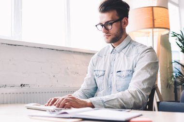 Modern bilgisayardaki ciddi erkek yazılım geliştirici klavye programı kodları, masaüstünde oturan, kablosuz internete bağlı teknolojiyle çalışan beyaz yetenekli bir adam e-posta yazarken