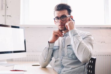 Özgüvenli erkek programcı, arka planda internet reklamınız için boş ekranlı bir evde otururken kameraya bakarak hesap bakiyesini kontrol etmek için operatörle konuşuyor.
