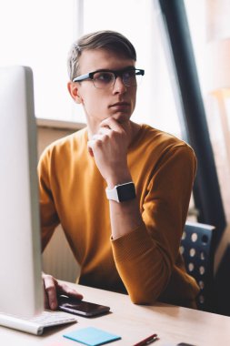 Kafkasyalı hippi, bilgisayardaki kablosuz bağlantıyı kuruyor. Ofis bilgisayarında kalıyor. Gözlüklü genç adam, modern teknolojiye uygulama yüklerken başka yöne bakıyor.