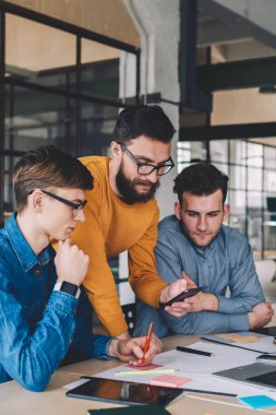 Beyaz tenli genç, iletişim, iletişim ve ortaklık kavramında iş birliği yaparken cep telefonundan mesajlar yolluyor ve mesajlar yolluyor.