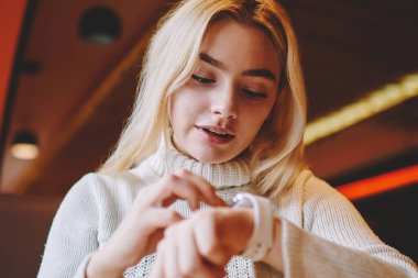 Genç bir kadın mesaj ve bildirimleri kontrol etmek için giyilebilir bilgisayar kullanıyor. Kafe içinde öğrenim görürken hippi kız dokunmatik ekranda tıkırtı çalışmak için zaman ayırmak için modern akıllı twatch uygulamasını kullanıyor.