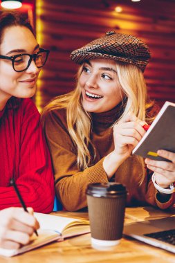 Mutlu kız öğrenci kafe iç ile dizüstü bilgisayar, neşeli kızlar samimi bir ortam içinde serbest başlangıç için yaratıcı fikirler tartışırken öğrenme ortak proje tamamlamak için işbirliği