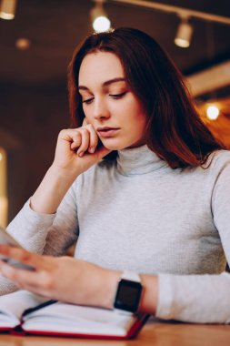 Posta telefon üzerinde uygulamada ödeme için girişlerle kontrol dalgın genç kadın kafeterya, öğrenme sırasında cep telefonu üzerinde ciddi kız öğrenci üniversitenin web sayfasında haber okuma göz