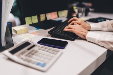 Modern ofis ortamında klavyede yazı yazan, ileri yaşlarda aktif istihdam ve teknoloji kullanımına odaklanan, eller ve ofis araçlarına odaklanan yaşlı beyaz erkek profesyonel.