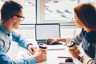 Arkadan görünüşü ve erkek öğrenci dizüstü bilgisayar ekranı, sahte hakkında bilgi alan coworking içinde işbirliği sırasında fikirleri tartışmak meslektaşları gözatmak için kullanarak ortak proje için araştırma yapma
