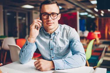 İş, hizmet operatör bankacılık ile telefon görüşmesi sırasında kameraya bakarak Eyewear genç işadamı telefon görüşmeleri yapma telefon tarifeler ile portre profesyonel erkek Yöneticisi memnun