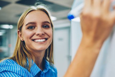 Flipchart bilgi öğrenme, proje planlama kurulu yaratıcı fikirler notu oluşturma kamera bakarak yaratıcı kadın tasarımcı için yazma neşeli sarışın öğrenci portresi yarım uzunluk