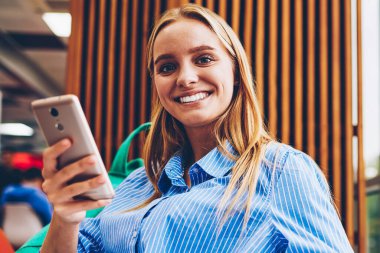 Proje, kameraya bakarak hücresel manifatura geribildirim üstünde posta kontrol başarılı kadın işçilerin çalışma planlama yapma smartphone üzerinden mesaj gönderme neşeli sarışın genç kadın portresi