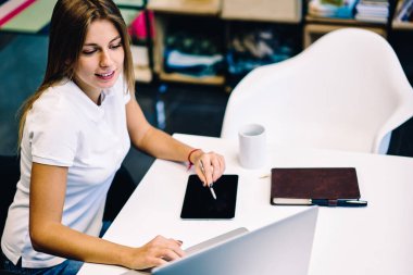 Üstten görünüm kroki tablete oluşturma yetenekli kadın web tasarımcısı modern uygulamalar ve yazılım sanatçı ve multimedya için netbook üzerinde gülümseyen kadın Illustrator memnun dizüstü bilgisayara bağlı