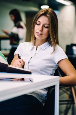 Not Defteri'nde, yaratıcı kadın yazar coworking zaman harcama fikirleri hakkında düşünme notlar yayın görevleri ödev yazma üniversite kitaplığında masada oturan kız öğrenci konsantre