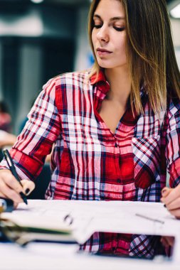 Kız öğrenci hazırlanması blueprint kurs Üniversite Kütüphanesi, yetenekli kadın tasarımcı çizim taslak proje düşünme accountings ve fikirleri hakkında çalışma sırasında için kağıt üzerinde oturan için konsantre