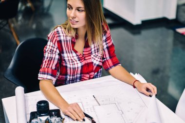 İleti örneği ve yaratıcı proje, zeki kız öğrenci uzak accountings grafikle çizerken seyir ders tamamlama üzerinde planları ile masaüstünde oturan genç kadın mimar