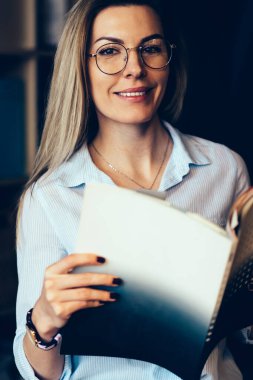 Yarım uzunluk portre çekici neşeli kadın Blogger gözlük gözleri koruma kapalı dinlenme zevk için. Kameraya Dergisi elele süre seyir muhteşem duygusal hippi kız