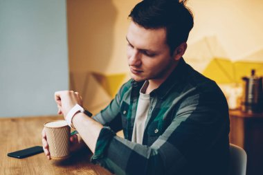 Kahve molası, modern giyilebilir Gadget'ı bildirim app eğlence kafeteryasında harcama dokunmatik ekran üzerinde düzenleme denetimini kullanarak teen hipster adam zamanında yönetme smartwatch bakarak Genç adam