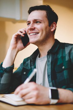 Not defterinde yazılı ve de coworking alanı, kredi hakkında danışmanlık sırasında bilgi notları memnun hizmet bankacılık yapma mutlu genç adam oturmuş telefonda konuşurken neşeli hipster adam