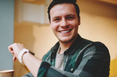 Bilek yararlı uygulamalar, mutlu erkek öğrenci kameraya seyir smartwatch özellikleriyle heyecan ile taşınabilir bilgisayarda modern dijital gadget giyen neşeli hipster adam portresi memnun