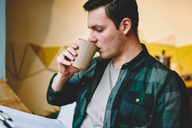 Sınav coworking uzayda içecek zevk için öğrenme analiz bilgisi verilerini tasarımı projenin, düşünceli erkek öğrenci klasörüne okuma sırasında kahve içme zeki hipster adam makaleler