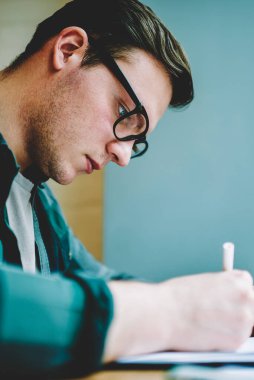 Zeki öğrenci bilgi ve yaratıcılık kullanarak başlatma deyim fikir için muhasebe yaparak öğrenme, ciddi hipster adam konsantre ödev görev için kompozisyon gözlük görünümünü kapat