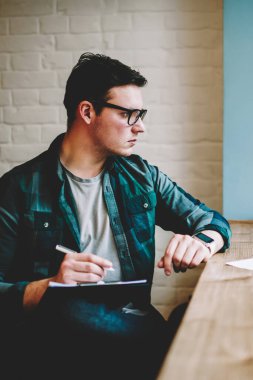 Dalgın hipster adam gözlük izlerken eğitim webinar e-öğrenme, proje için serbest tarama bilgilerini kroki çizim netbook üzerinde çalışan erkek tasarımcı üzerinde vakit dizüstü bilgisayar