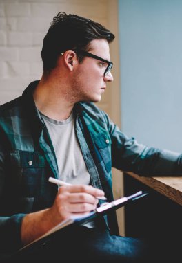 Ödev dizüstü bilgisayarda izlemek için arama öğretici zeki genç adam, düşünceli erkek freelancer oluşturma tasarım kroki uzaktan göz not defterinde çizim sırasında uygulama netbook üzerinde