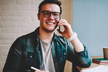 Bilgi eğitim, başarılı hipster adam alan coworking uzak iş üzerinde makale yazma sırasında telefon görüşmesi için dikkat çeken ise telefon danışmanlık ile neşeli adam portresi memnun