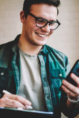 Mutlu erkek gözlük 4 g bağlantı kullanım chekcing posta üstünde hareket eden telefon, sosyal ağ smartphone kullanarak yeni arkadaşına teyit neşeli hipster adam için indirim almak ile memnun '