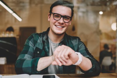 Dijital kol saati öğrenme kafe iç zamanında kontrol gözlük neşeli hipster adam portresi, genç erkek giyilebilir bilgisayar ile memnun mutlu olsun yeni ileti uyarısı