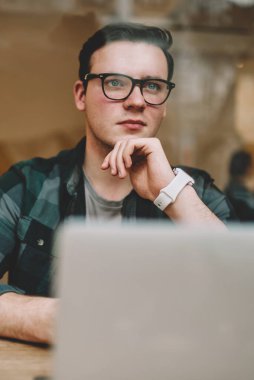 Ciddi erkek serbest meslek kafe iç, dizüstü bilgisayarda çalışma işlemi sırasında durulması gözlük netbook çevrimiçi eğitim yakın oturan çözümleri hakkında düşünme düşünce hipster adam