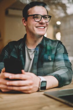 Smartphone için ağ oturma kafe iç ile teknoloji, kahve dükkanı iyi wifi ile uzaktan çalışma müreffeh erkek freelancer memnun kullanarak gözlük mutlu genç adam
