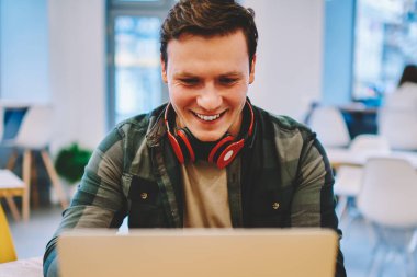 Online Oyunlar serbest zaman sırasında netbook üzerinde film izlerken gülen mutlu genç adam iyi kablosuz bağlantı Office'le coworking içinde dizüstü bilgisayar oynarken zevk heyecan hipster adam