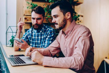 Konsantre erkek birlikte dizüstü üzerinden proje üzerinde işbirliği karar geliştiriciler hesaplamak, ev ödevi görevi kampus içinde netbook üzerinde araştırma yapmak için fikirler tartışırken ciddi hipster çocuklar BT