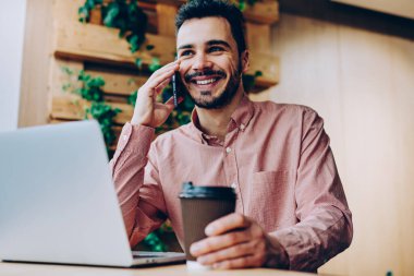 İş yerinde bilgisayarla uzaktan telefon görüşmesi yapan başarılı genç, serbest çalışan yakışıklı, gülümseyen hippi kahve molasında cep telefonu sohbetinden zevk alıyor.
