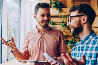İş planı için birlikte tartışmaya başarılı erkek startuppers gülümseyen ve mimik, iş bilgileri office coworking toplantısı hakkında samimi konuşmayı mutlu hipster çocuklar