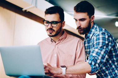 Yetenekli erkek öğretmen, okulda öğrencilere programlama araçlarını anlatıyor. Hipster çocuk, arkadaşa bilgisayardaki yazılımı güncellemesi için yardım ediyor.