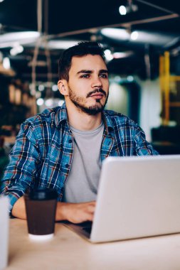 Düşünceli erkek freelancer uzay, netbook ve wifi öğrenme için üniversite kitaplığında kullanarak düşünceli genç öğrenci coworking içinde dizüstü bilgisayar ile oturup çalışma projesi için fikir üzerinde durulması