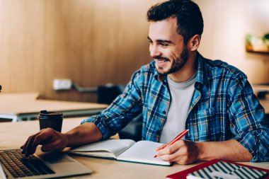 Neşeli genç erkek öğrenci eğitim webinar ders planı, mutlu yetenekli freelancer Gözat video içinde not etmek için kişisel blog makale oluşturma netbook üzerinde hazırlanması dizüstü bilgisayar üzerinde zevk