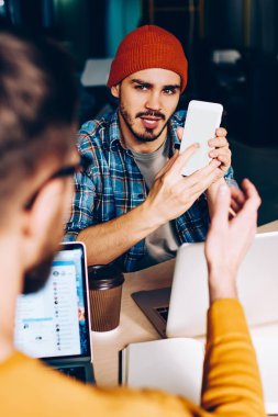 Erkek, yeni akıllı telefon ve modern uygulama hakkında konuşan meslektaşını dinliyor. Profesyonel olarak, dijital cihazın iyi bir bağlantı göstermesi hakkında konuşuyorlar.