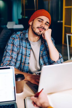 Üniversitede öğrenmek için dizüstü bilgisayarın başına oturmuş kameraya bakan düşünceli hippi adam. İş sırasında iş arkadaşlarıyla bir şeyler hayal eden bir erkeğin kırpılmış görüntüsü.