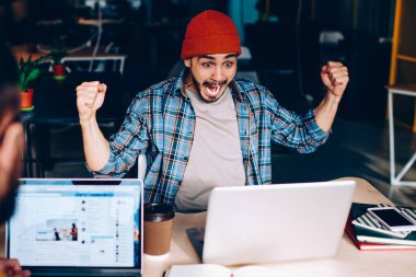 Coşkulu erkek futbol fanatiği takım maçının zaferine hayret ediyor. Çalışma sürecinde çığlık atıyor ve neşeleniyor. Duygusal hipster adam yarışmada kazanmanın harika haberlerini kutluyor.