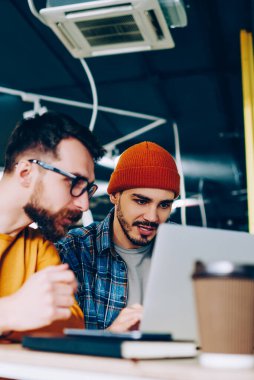 Yetenekli erkek dizüstü bilgisayardaki yazılımı güncellerken programlama üzerine yoğunlaşır. Hippi çocuklar birlikte eğitim web sitesinde webinar izlerler.