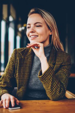 Mutlu sarışın genç kadın kahve dükkanında seyir harcama boş zaman zaman şık ceket giymiş. Neşeli hippi kız el café iç ahşap masada oturan smartphone ile