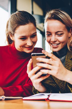 Canlı izlerken olumlu kız öğrenci blog Smartphone cep telefonu ile akışında bağlı 4 g internet kafede sınava hazırlık sırasında. Mutlu genç kadın telefonu sosyal ağlar komik yorum okuma