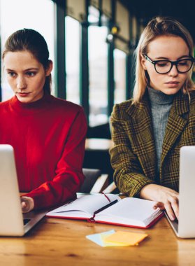 Dizüstü bilgisayarda kablosuz 4 g için bağlı çalışan kadın grafik tasarımcıları konsantre Internet üzerinde serbest coworking. Dalgın iki akıllı öğrenciler netbook'lar üzerinde web sitelerinde bilgi arama