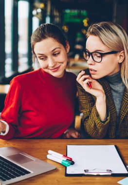 İki şüpheci yetenekli öğrenciler dizüstü bilgisayarda internet sitesinde tasarım tutorial online izlerken bilgi analiz ve tartışmak için kablosuz 4 g bağlı oturma alanı coworking internet