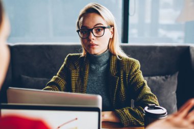 Portre ciddi kadın Freelancer giyinmiş şık kıyafetiyle teamworking meslektaşı dizüstü bilgisayarlar ile uzaktan kablosuz 4 g için bağlıyken kameraya bakarak alan coworking içinde Internet